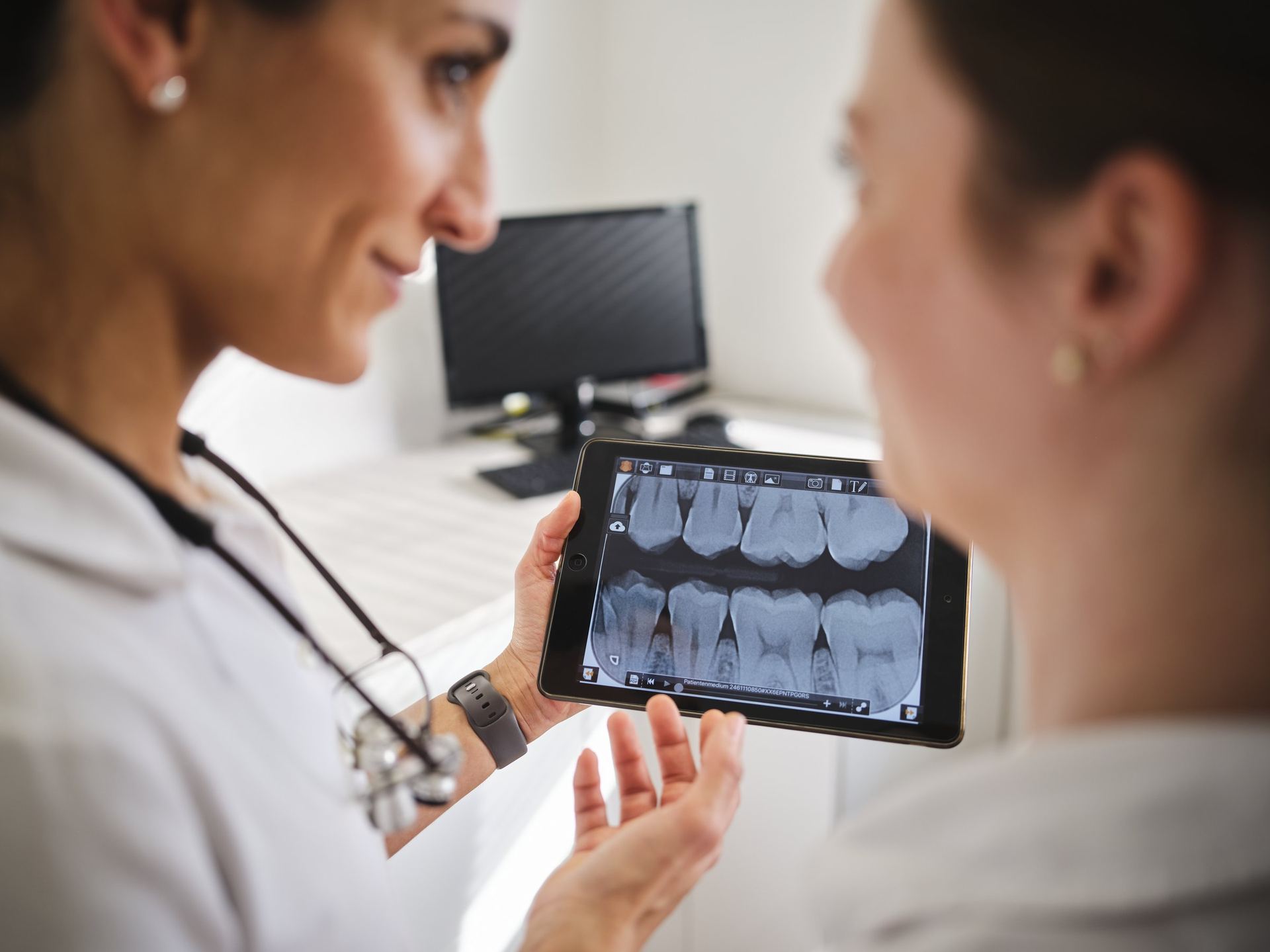 Zahnärztinnen besprechen digitale Röntgenaufnahmen am Tablet